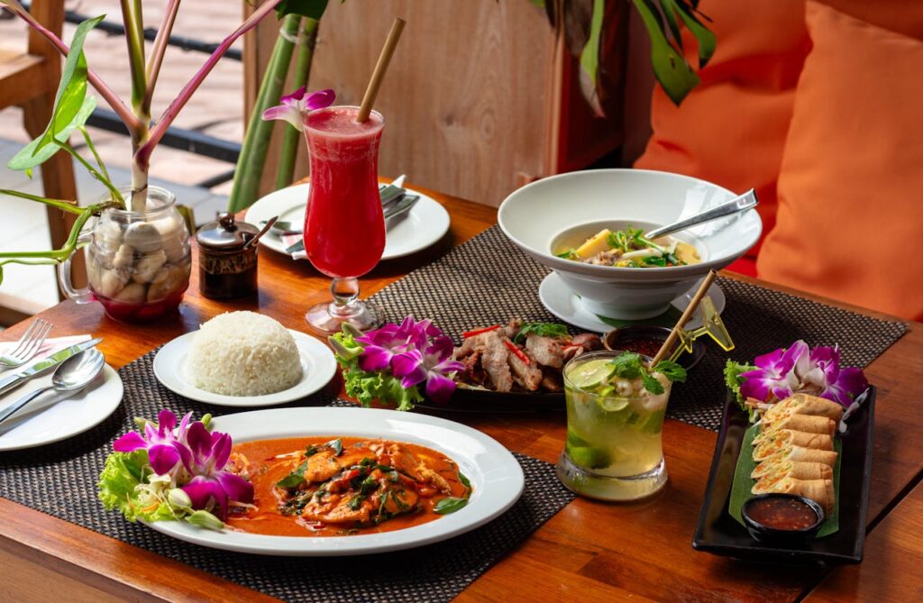 A vibrant display of Thai dishes with floral garnishes and refreshing drinks.